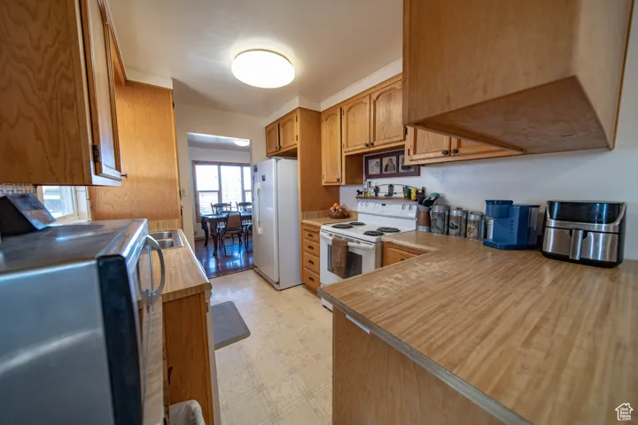 Kitchen featuring light floors, white appliances, light countertops, and brown cabinets