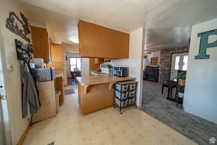 Kitchen featuring light countertops, a breakfast bar area, a textured ceiling, white appliances, and light floors