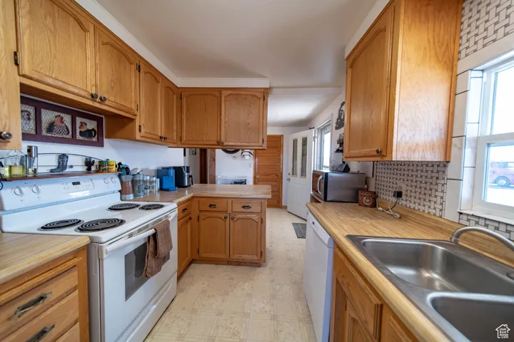 Kitchen with white appliances, healthy amount of natural light, light flooring, and a peninsula