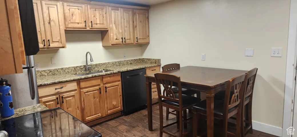 Kitchen with light stone counters, dark wood-style flooring, and black appliances