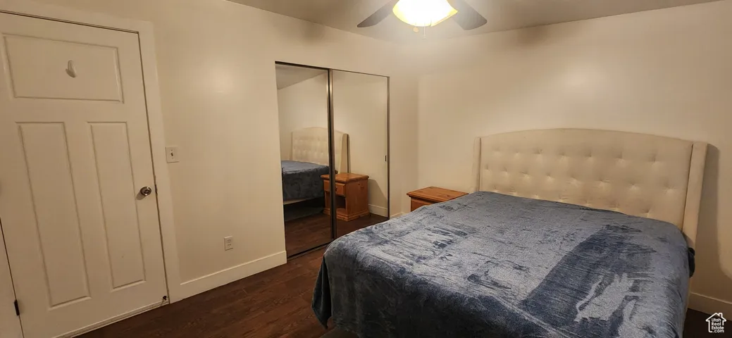 Bedroom with dark wood-style flooring, ceiling fan, and a closet
