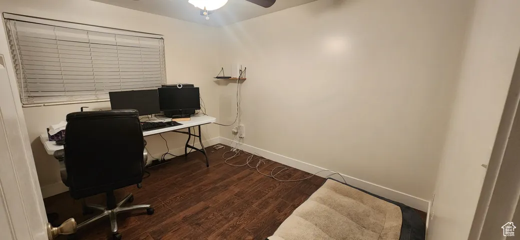 Office featuring dark wood-type flooring and a ceiling fan