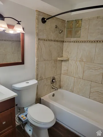 Bathroom with shower / washtub combination, dark wood finished floors, and vanity