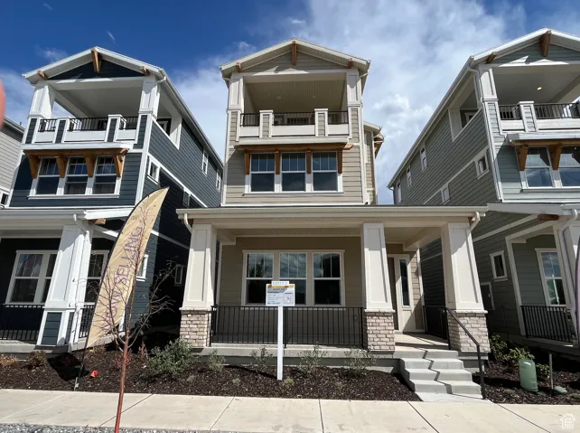 View of front of house featuring covered porch, stone siding, and a balcony
