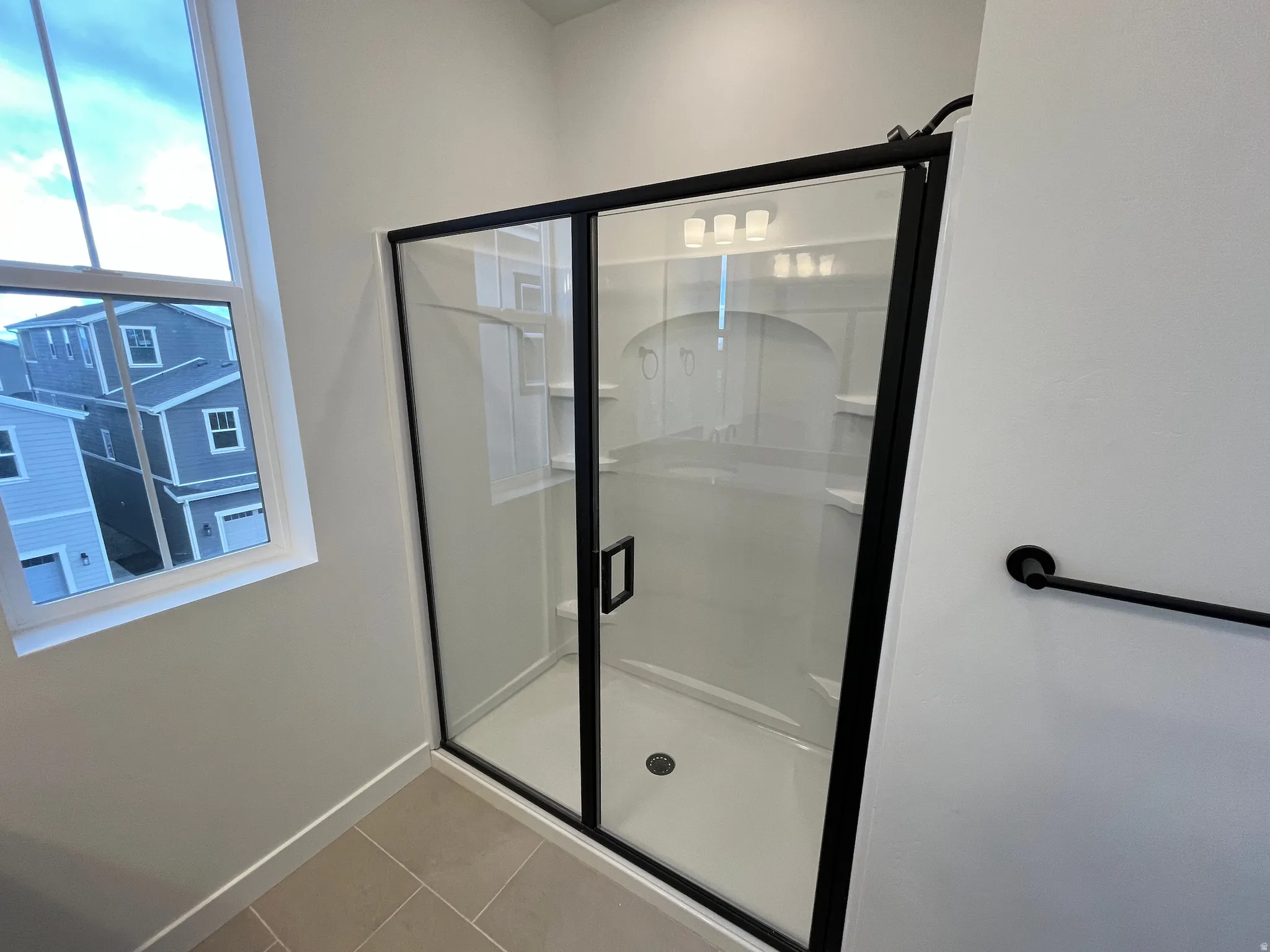 Bathroom featuring light tile patterned floors and a stall shower