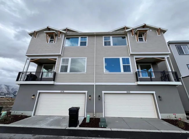 Rear view of house with a balcony, driveway, stucco siding, and an attached garage