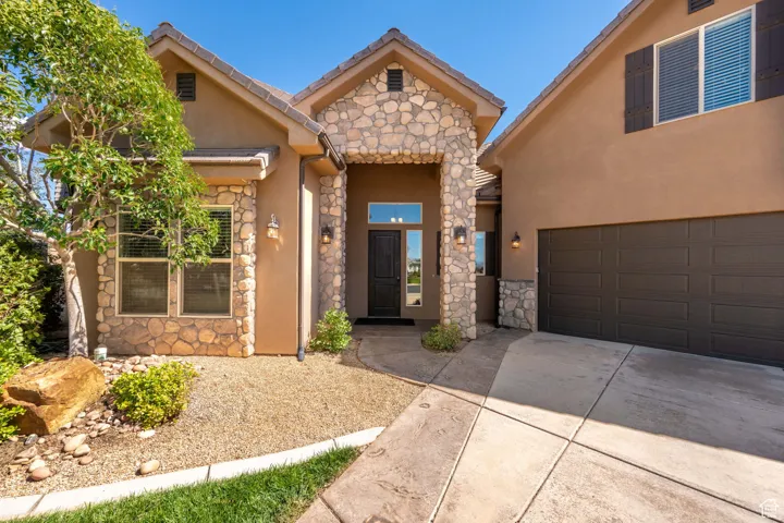 View of front of home featuring stone siding, concrete driveway, stucco siding, and an attached garage