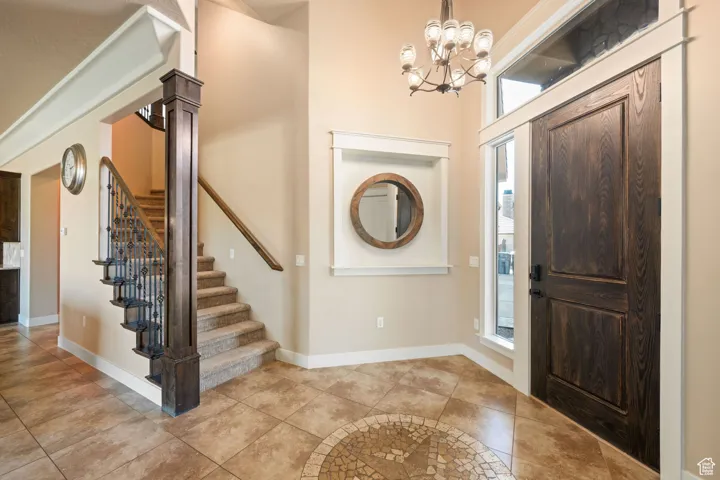 Tiled entrance foyer with stairway and a chandelier
