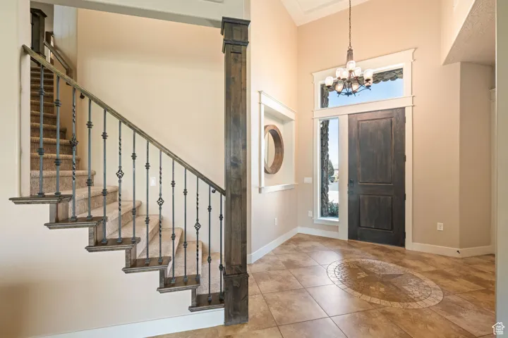 Entrance foyer with light tile patterned floors, a chandelier, and a high ceiling