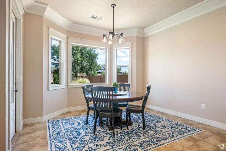 Dining room with ornamental molding, a chandelier, and a textured ceiling