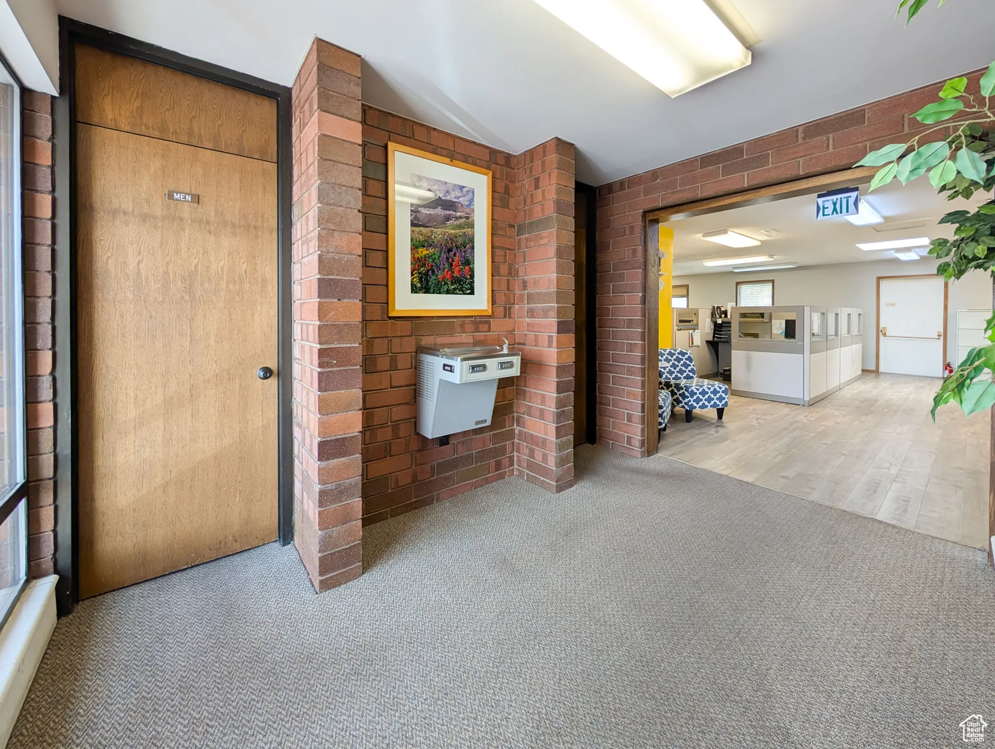 Corridor featuring brick wall, carpet, and lofted ceiling