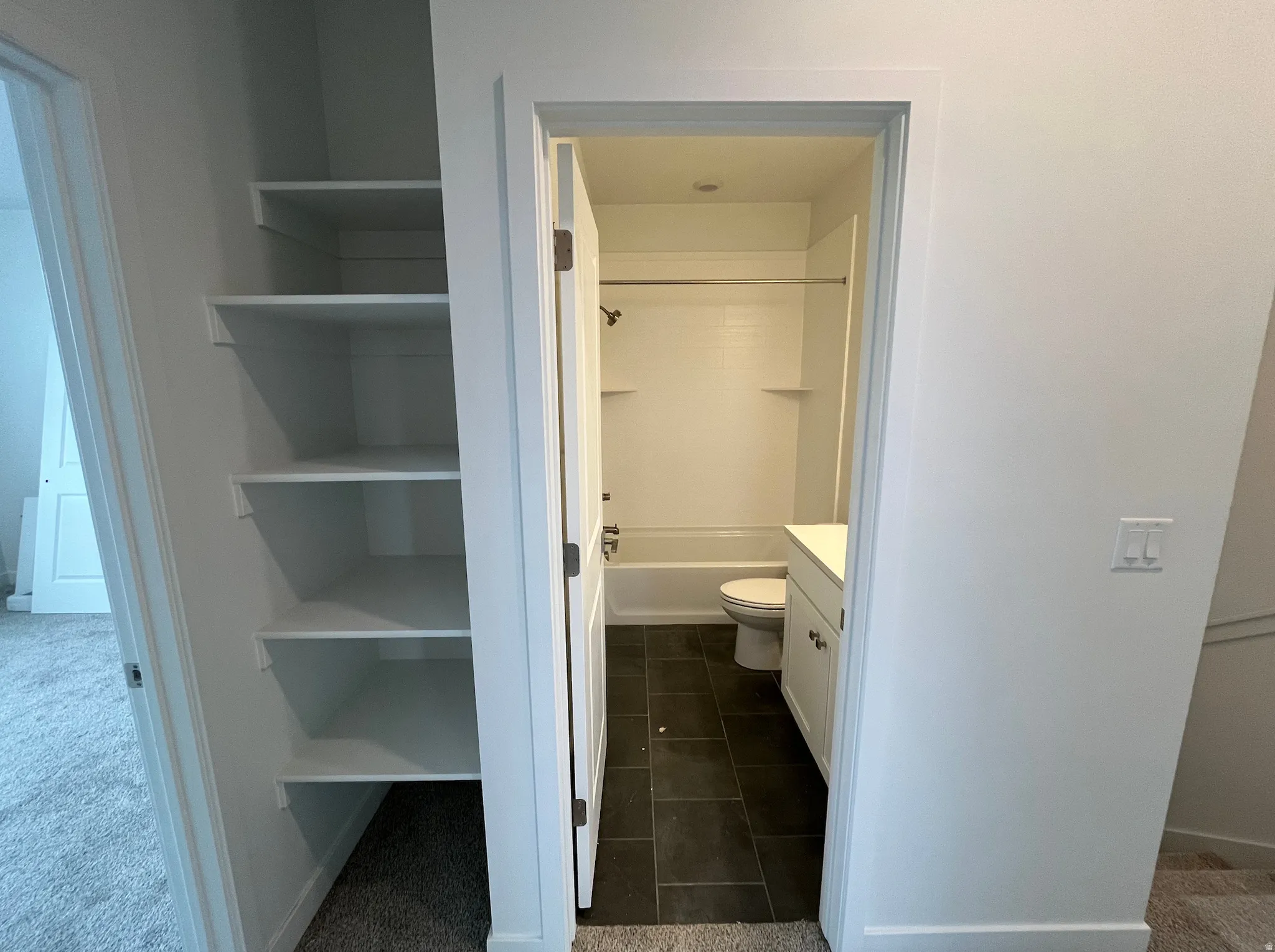 Bathroom with vanity, bathtub / shower combination, dark colored carpet, and dark tile patterned floors