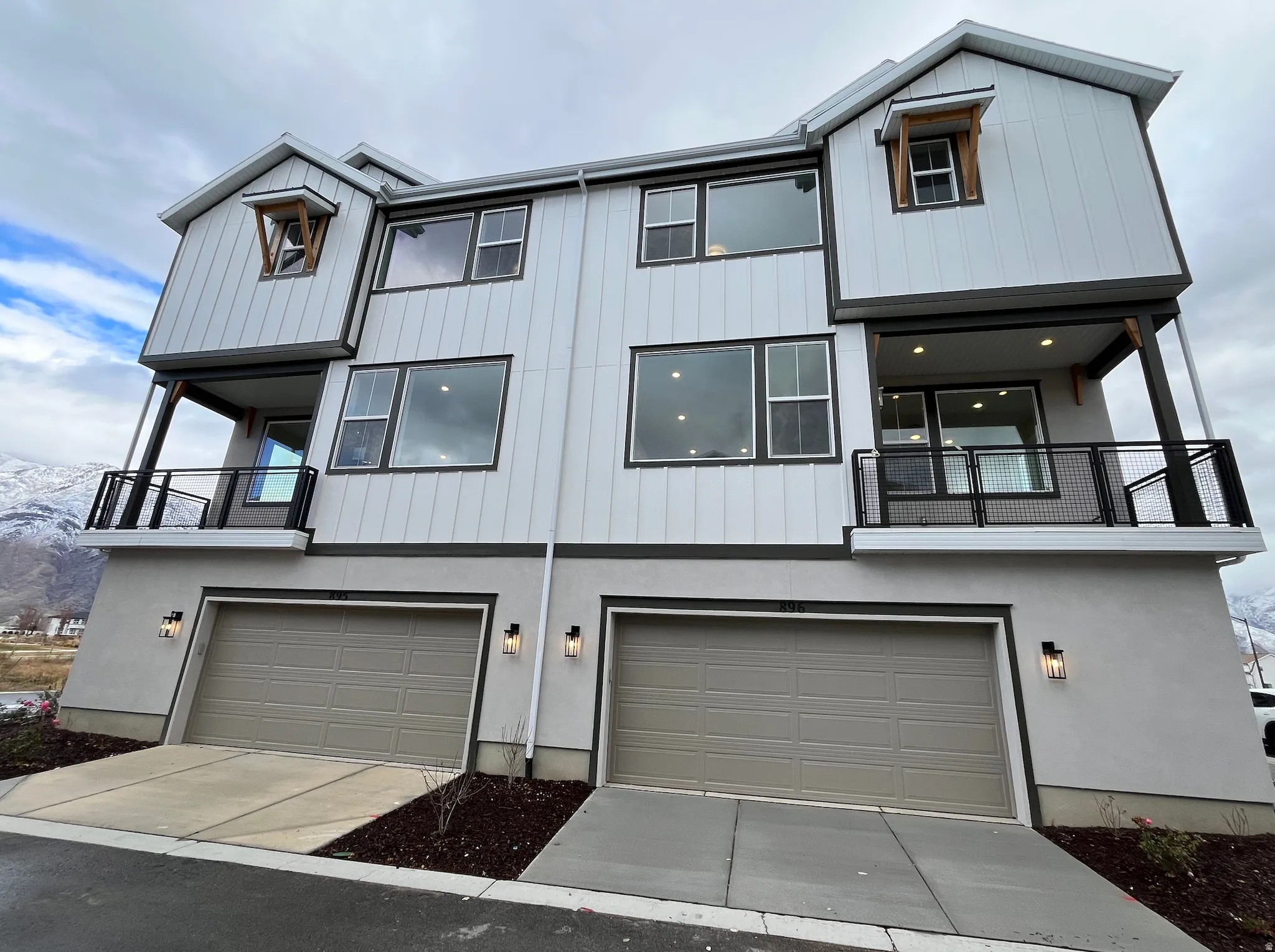 View of front of property featuring a balcony, driveway, an attached garage, and stucco siding