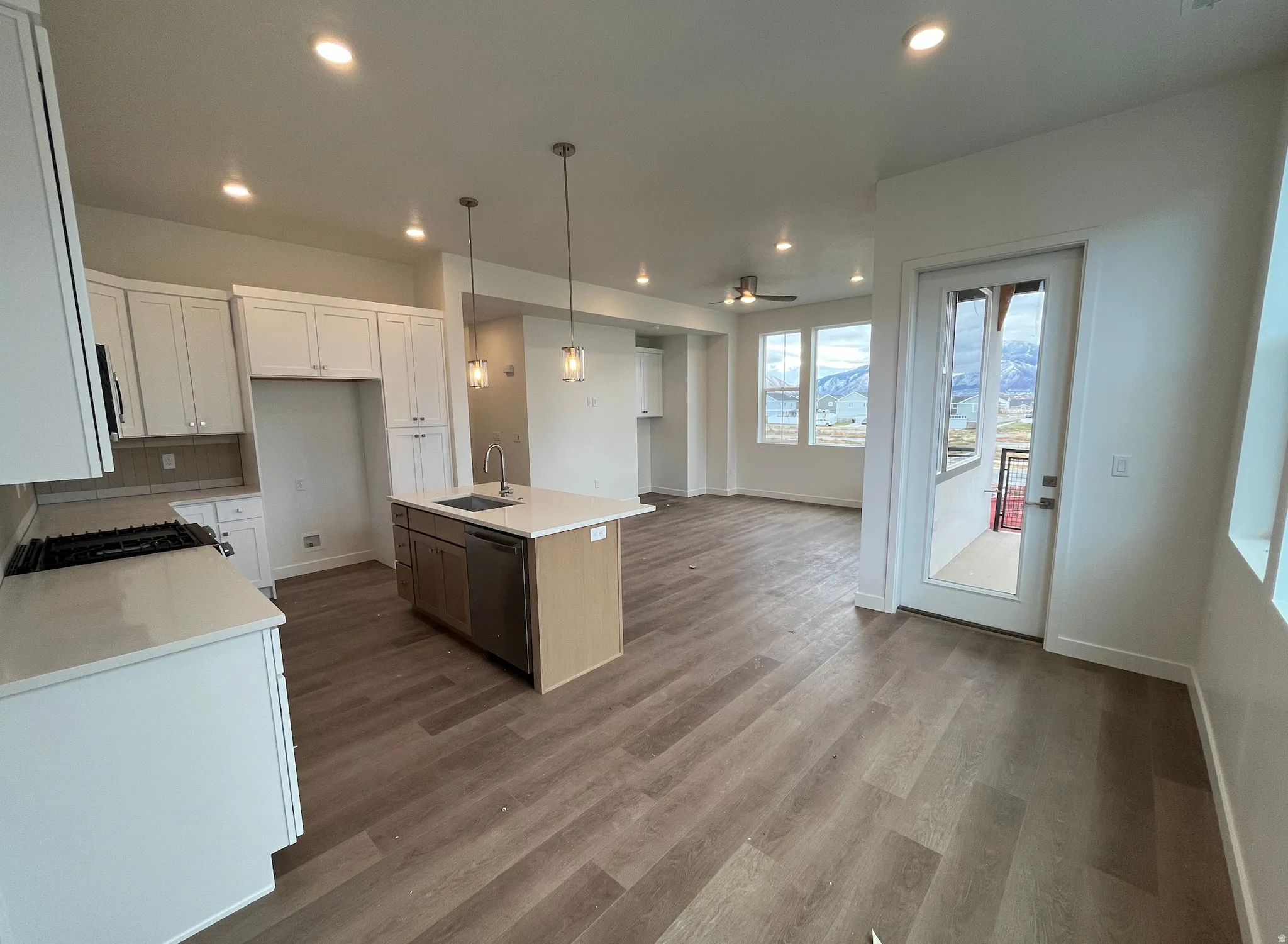 Kitchen with white cabinets, hanging light fixtures, a center island with sink, open floor plan, and recessed lighting