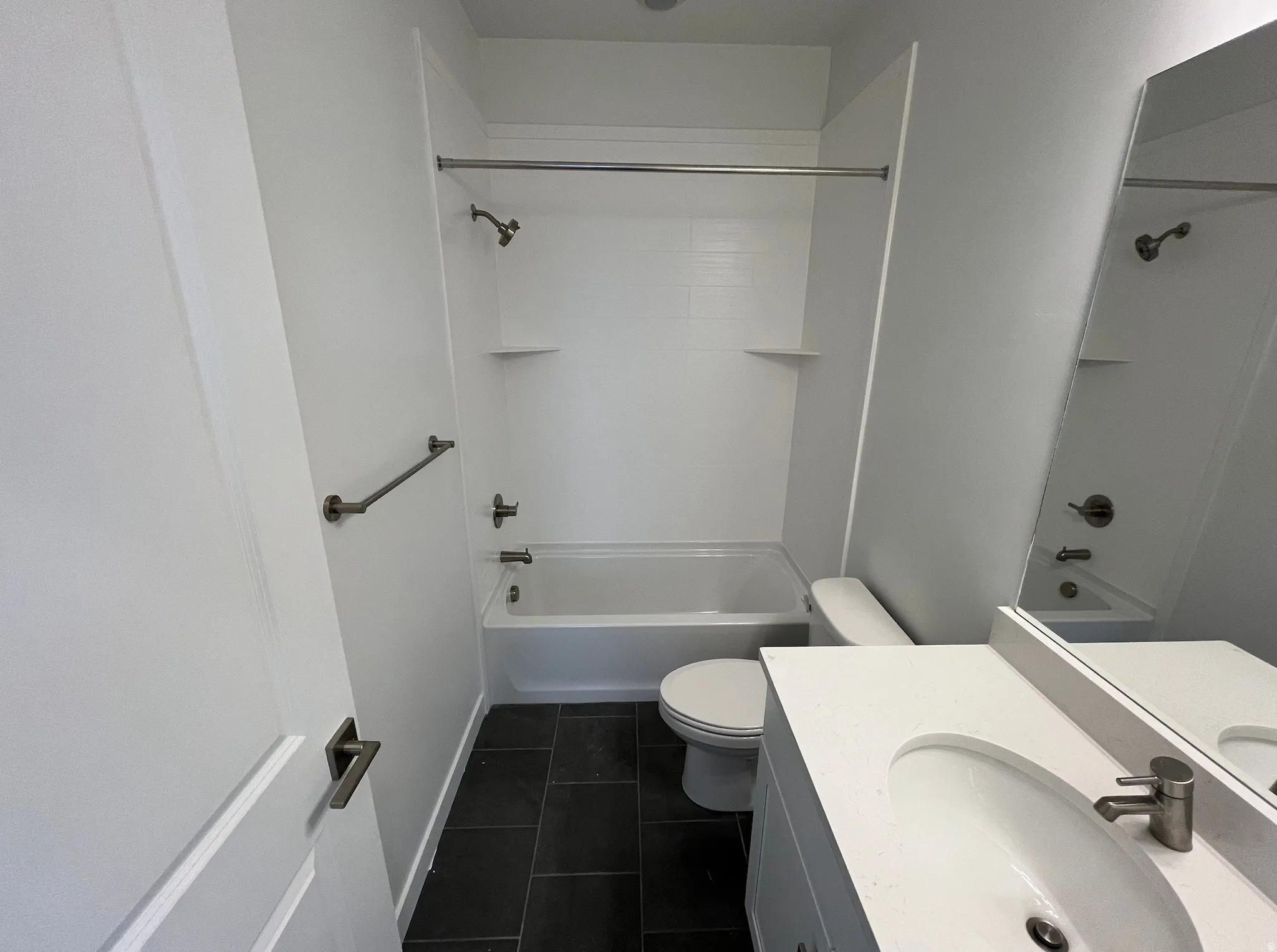 Full bathroom featuring bathing tub / shower combination, vanity, and dark tile patterned flooring