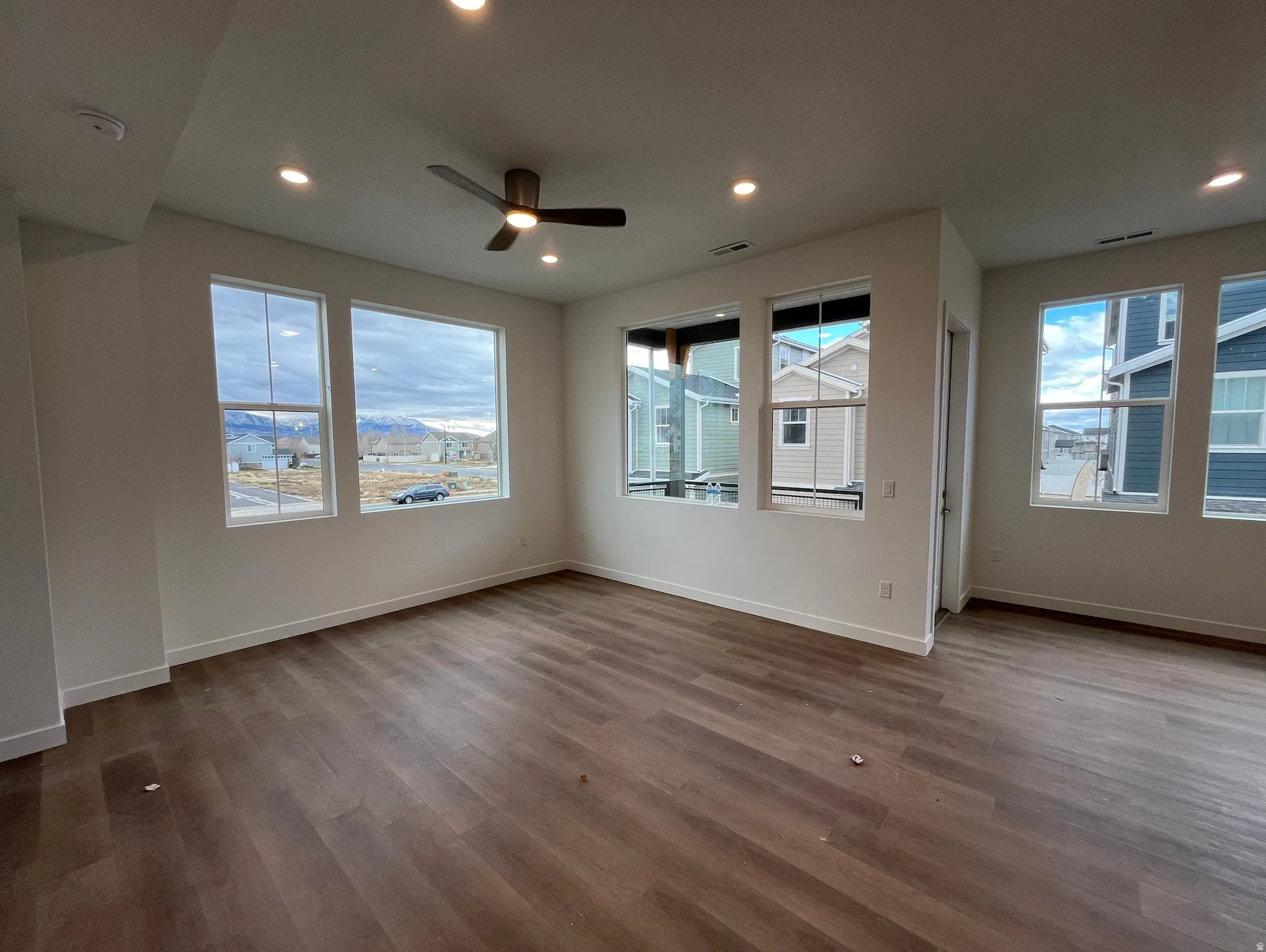 Spare room featuring wood finished floors, ceiling fan, healthy amount of natural light, and recessed lighting