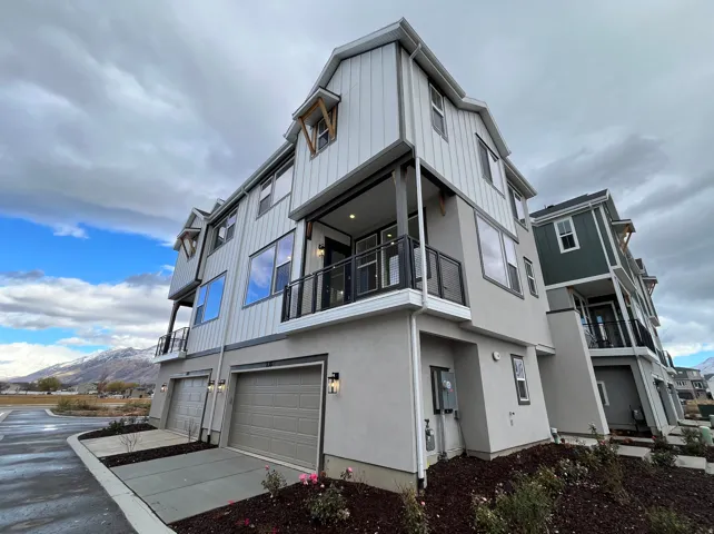 View of side of home featuring a balcony, driveway, a garage, stucco siding, and a mountain view