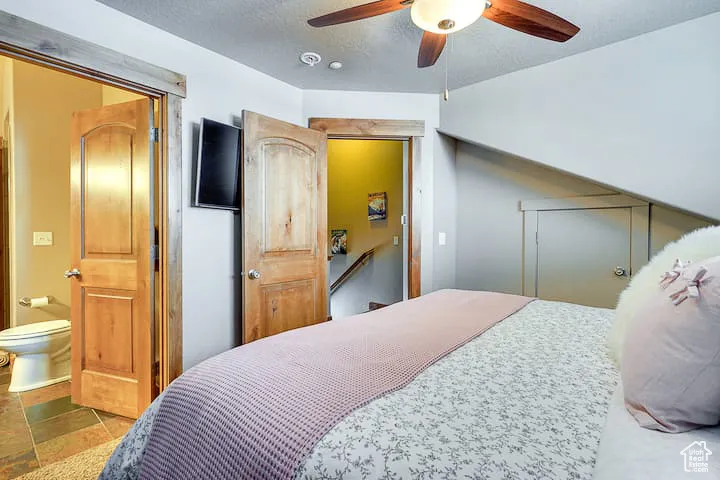 Bedroom with a textured ceiling, a ceiling fan, and ensuite bathroom