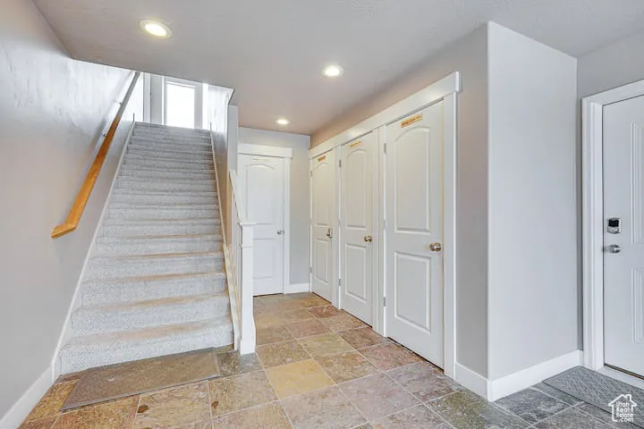 Stairway with recessed lighting and stone tile flooring