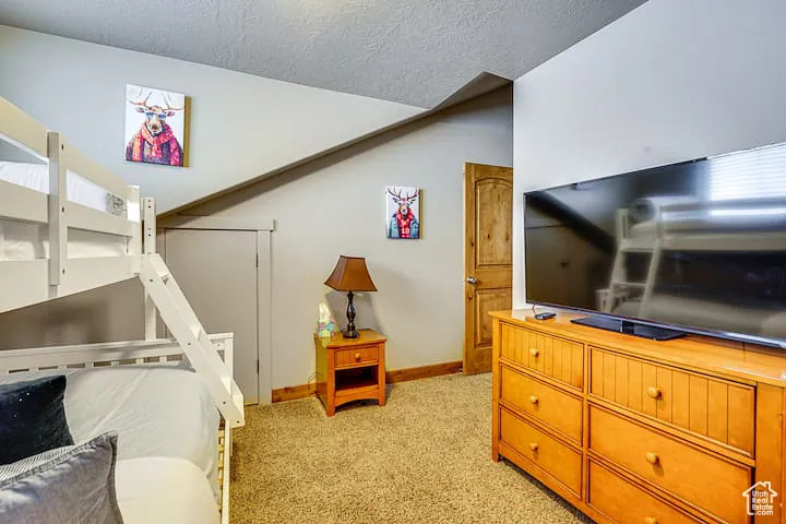 Bedroom featuring light colored carpet and a textured ceiling