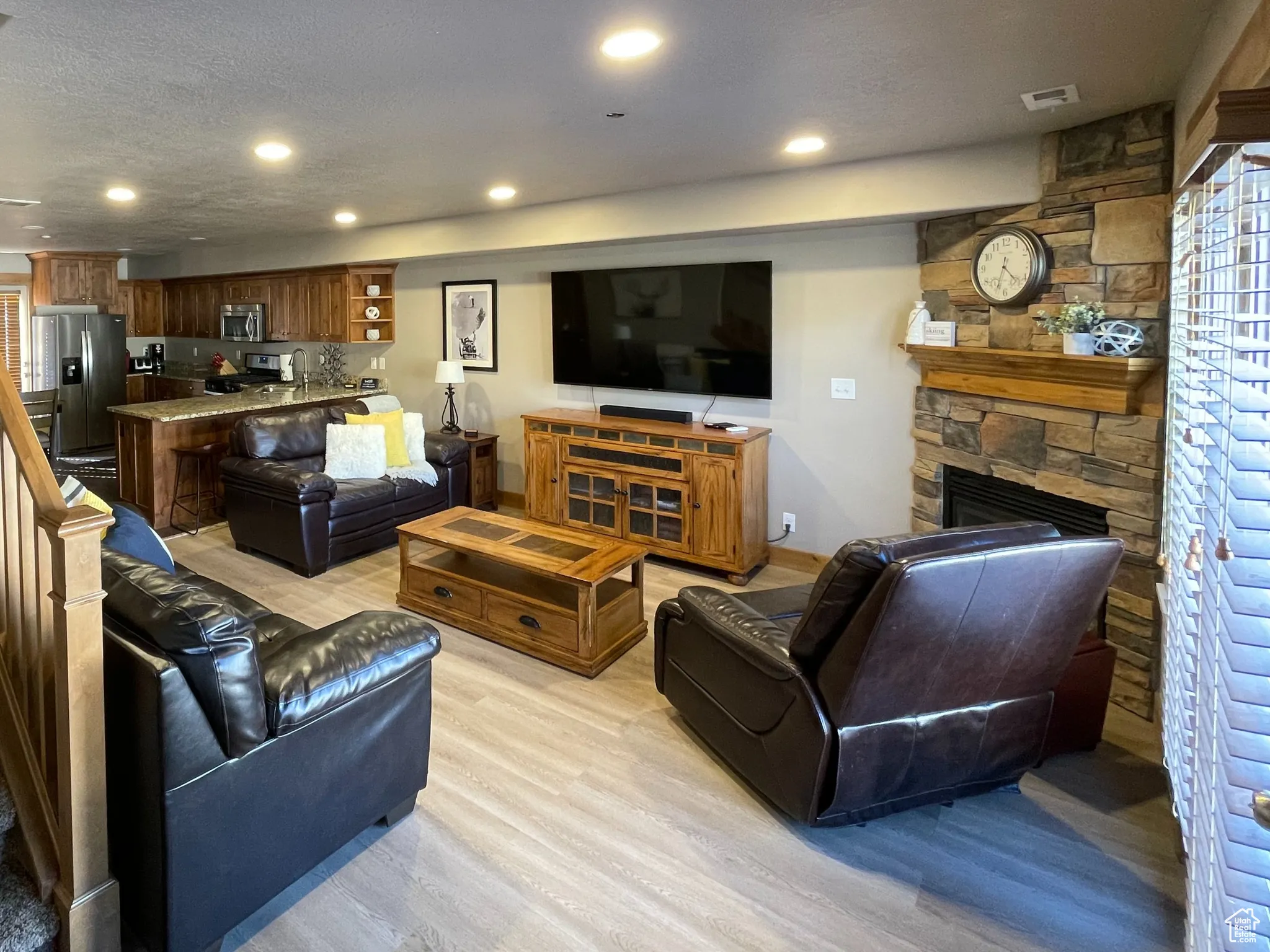 Living area with a fireplace, light wood finished floors, stairs, recessed lighting, and a textured ceiling