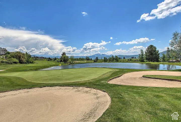 Surrounding community with a water and mountain view, golf course view, and a yard