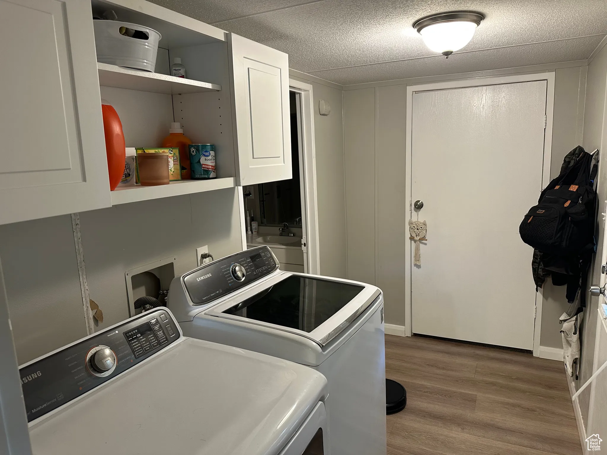 Washroom featuring dark wood-style flooring, cabinet space, a textured ceiling, and independent washer and dryer