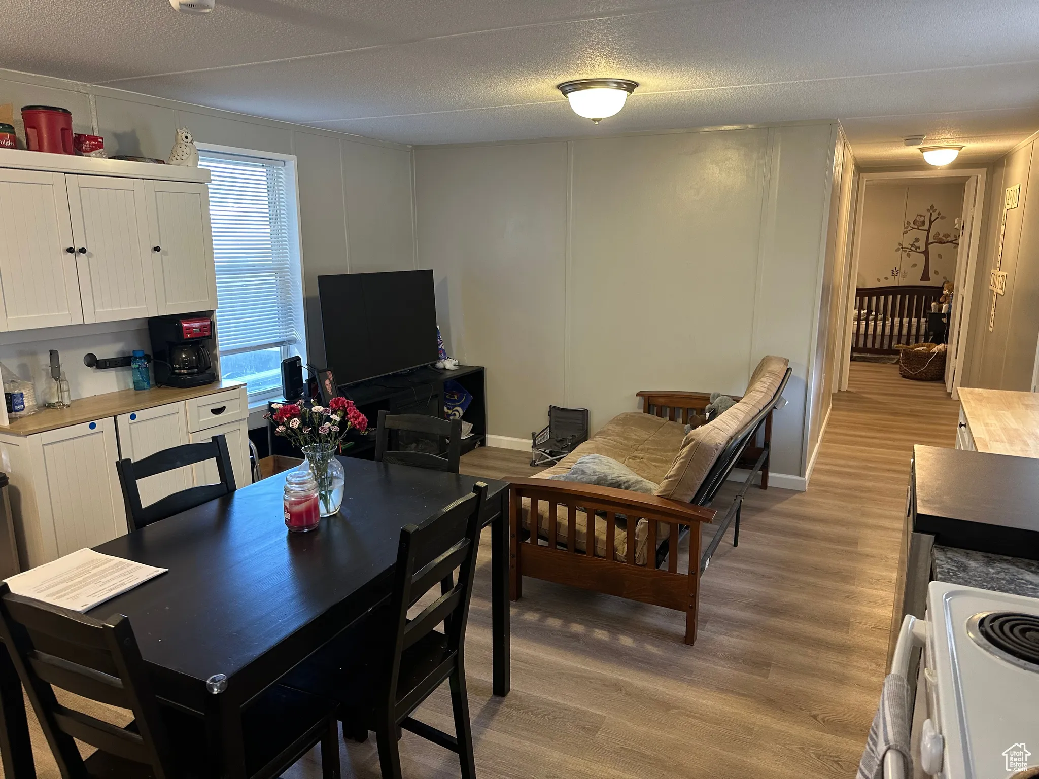 Dining room with a decorative wall, light wood-type flooring, and a textured ceiling