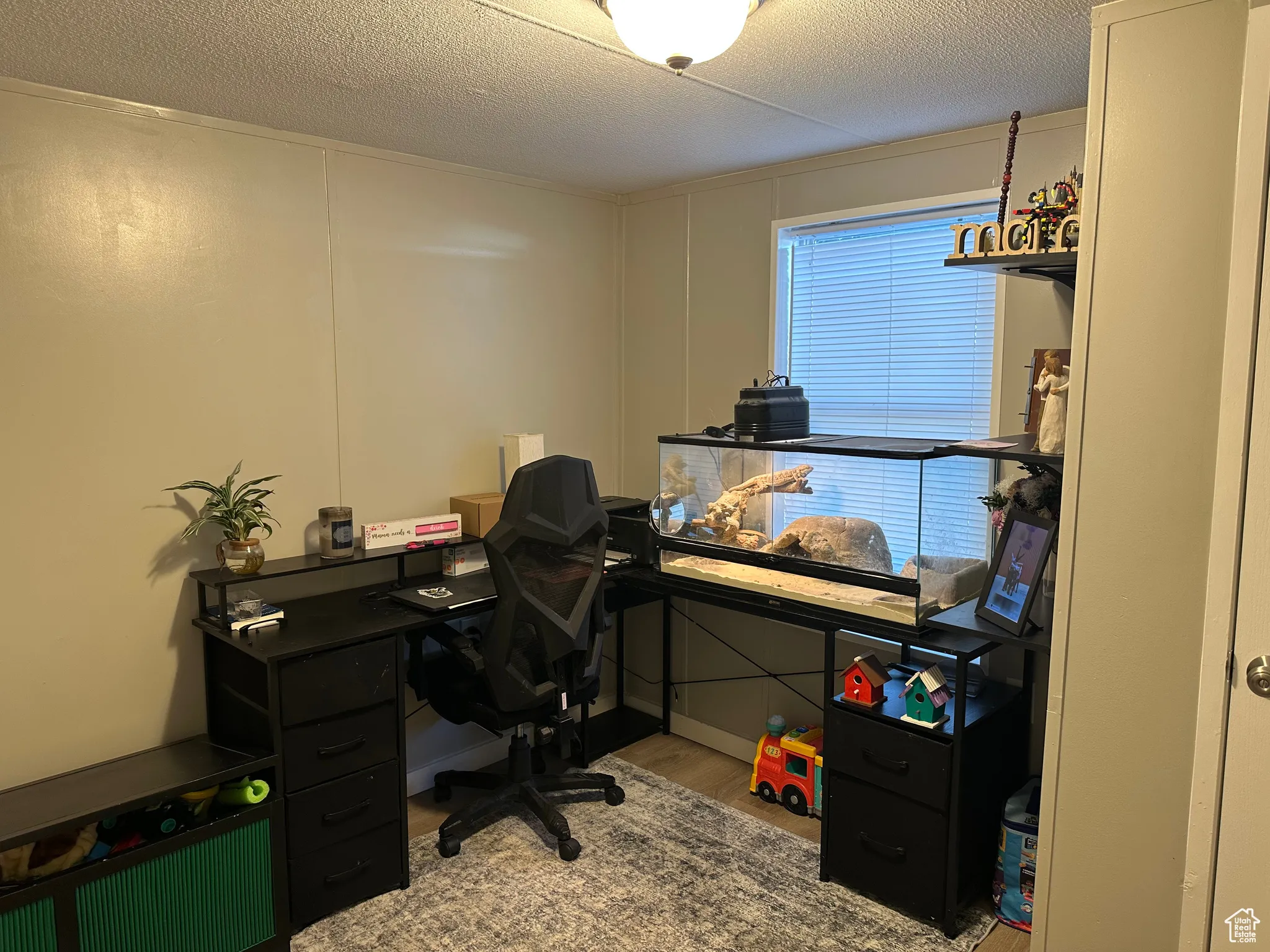 Office with a decorative wall, light wood-style floors, and a textured ceiling