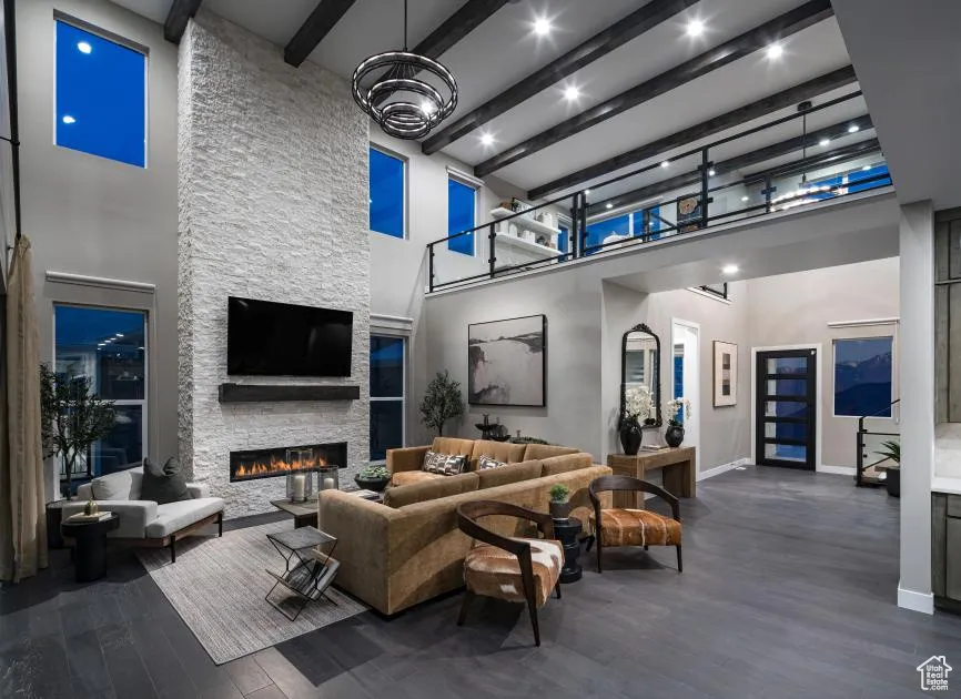 Living area with beam ceiling, dark wood finished floors, a fireplace, and a towering ceiling