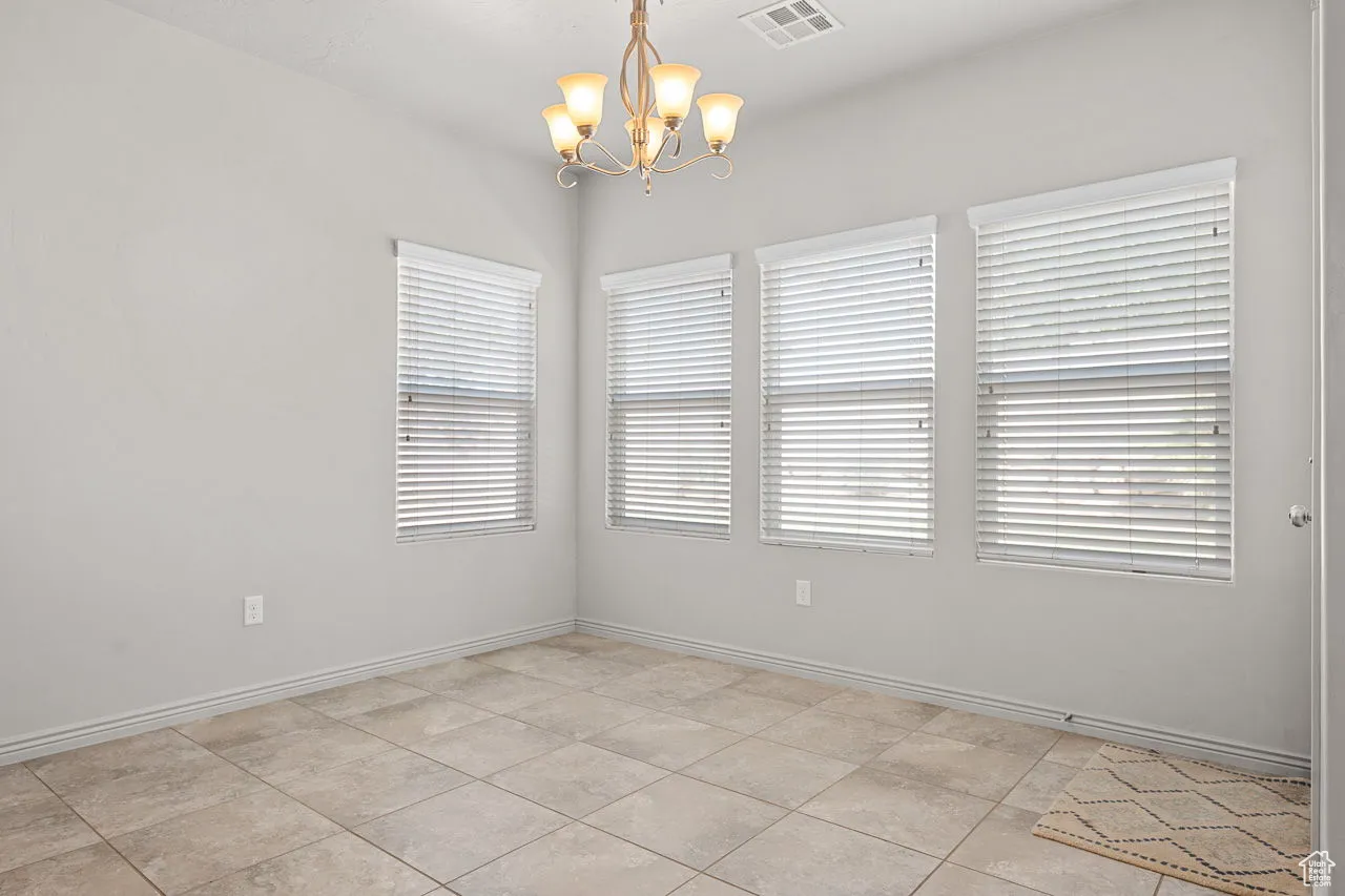 Spare room featuring a chandelier and light tile patterned floors