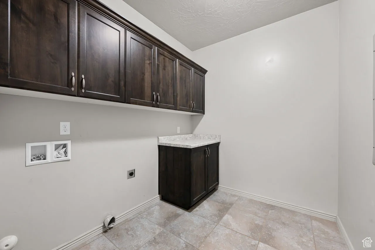 Washroom with cabinet space, a textured ceiling, washer hookup, and electric dryer hookup