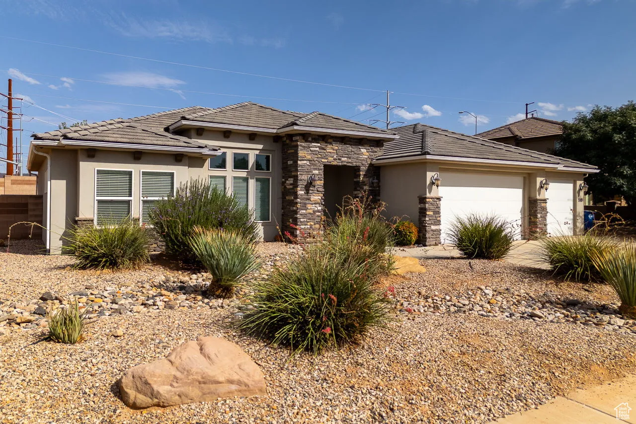 Prairie-style house featuring stone siding, stucco siding, and a garage
