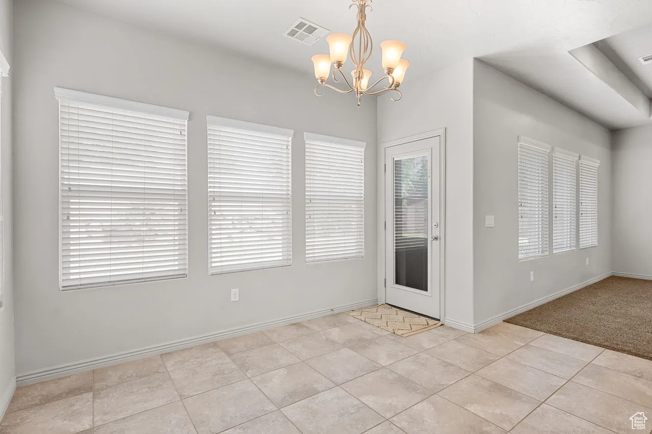 Unfurnished dining area featuring a chandelier and light tile patterned floors