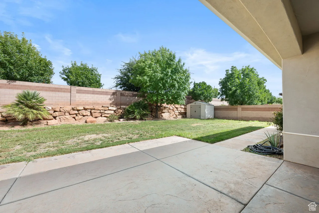 Fenced backyard featuring a patio and a storage unit