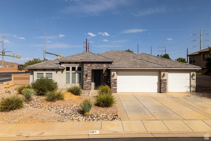 View of front facade with stone siding, a garage, stucco siding, and concrete driveway