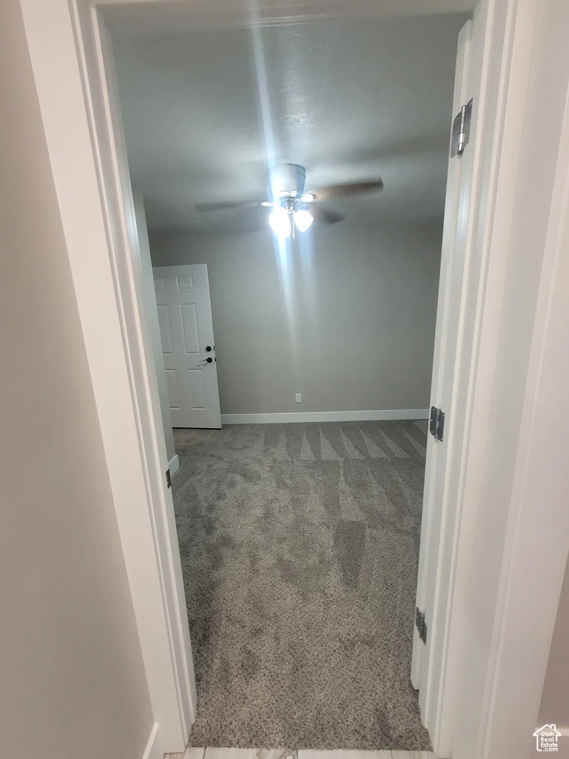 Unfurnished room with light carpet and a ceiling fan