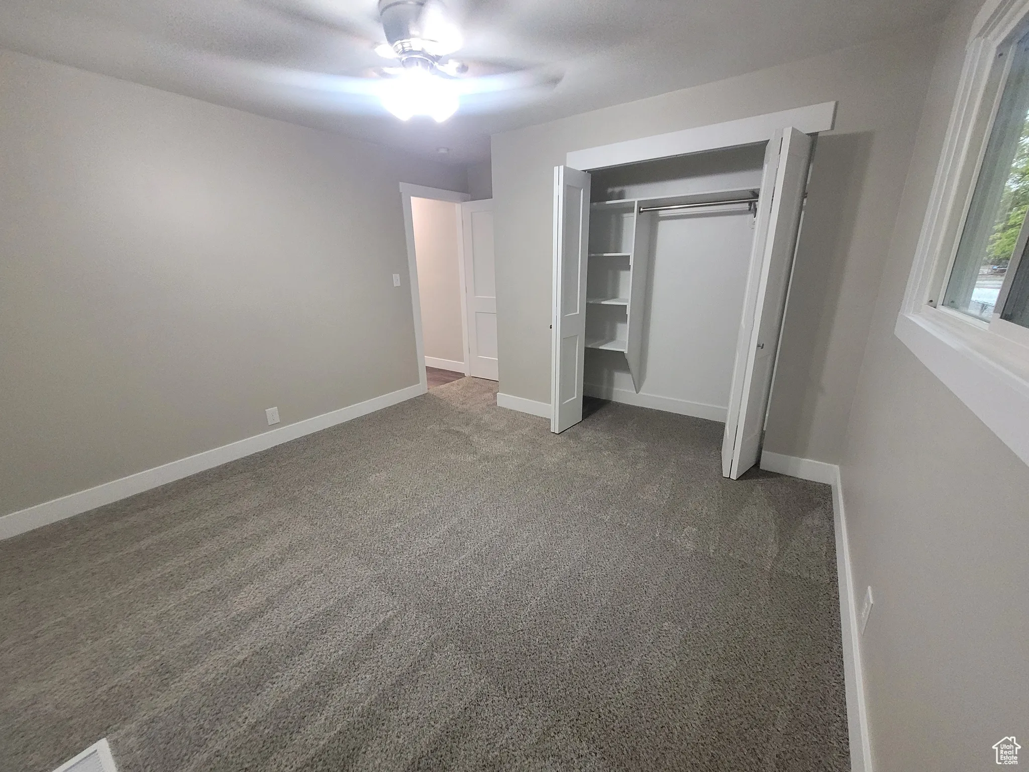 Unfurnished bedroom featuring carpet floors, a ceiling fan, and a closet