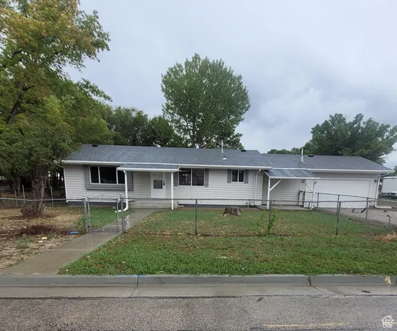 Ranch-style home with a fenced front yard, a porch, a gate, and an attached garage