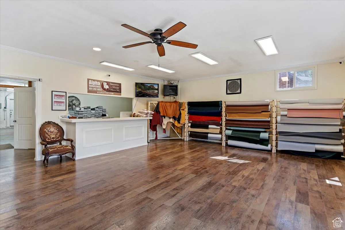 Interior space with dark wood-style floors, crown molding, and ceiling fan