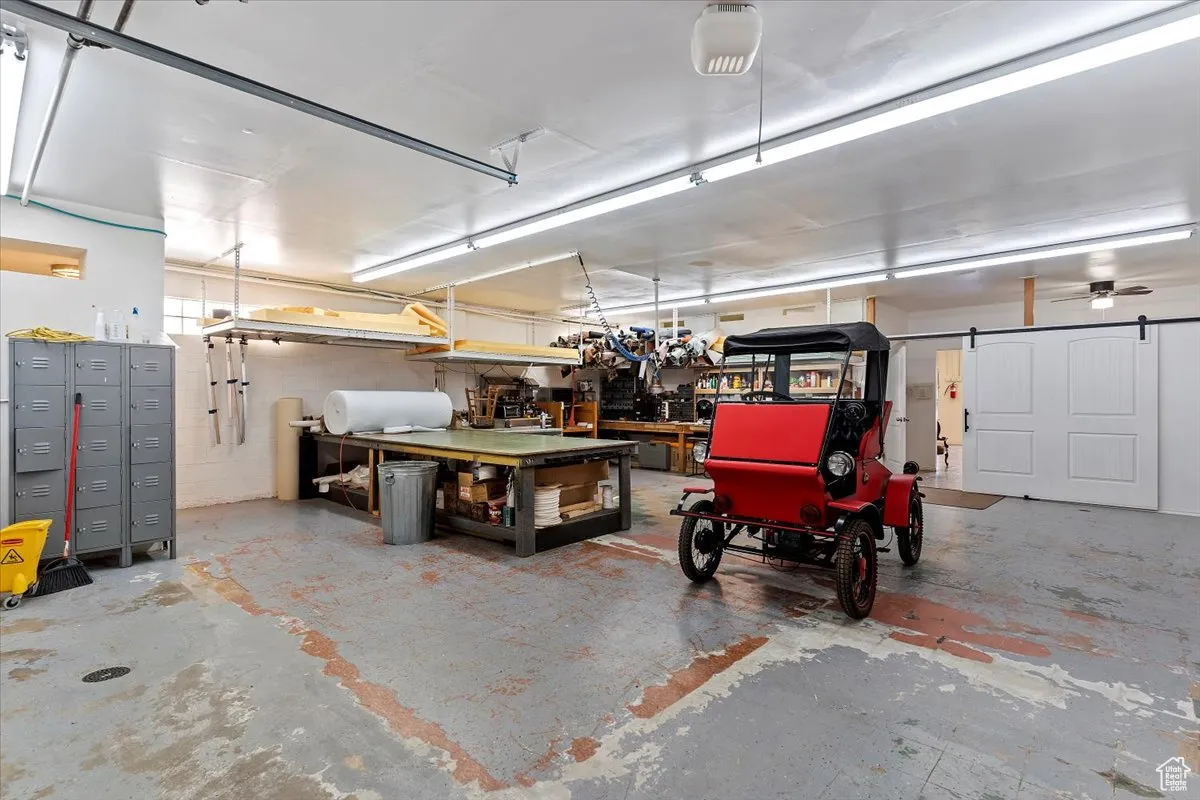 Garage featuring concrete block wall, a garage door opener, and a workshop area