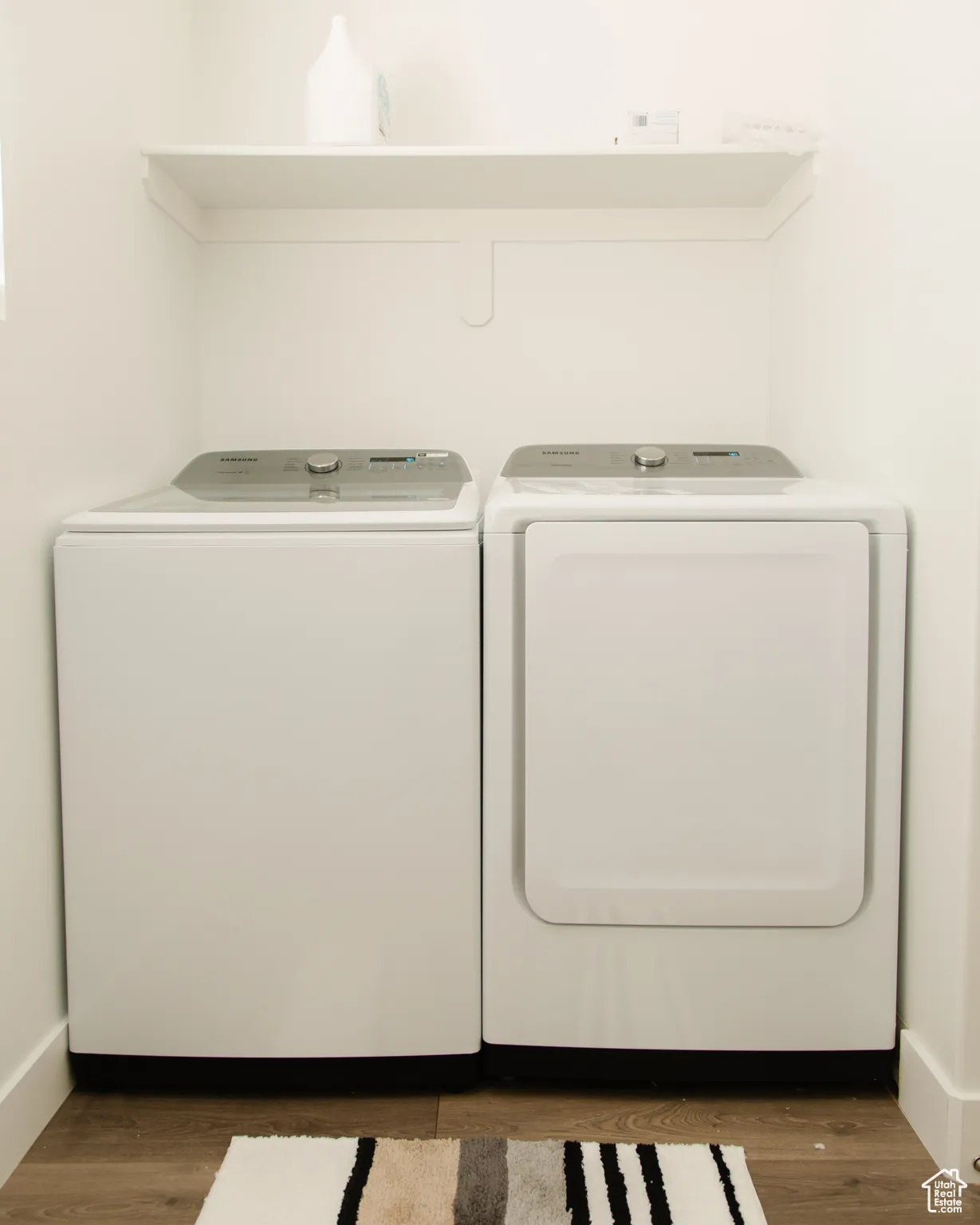 Washroom with dark wood-style floors and washer and clothes dryer