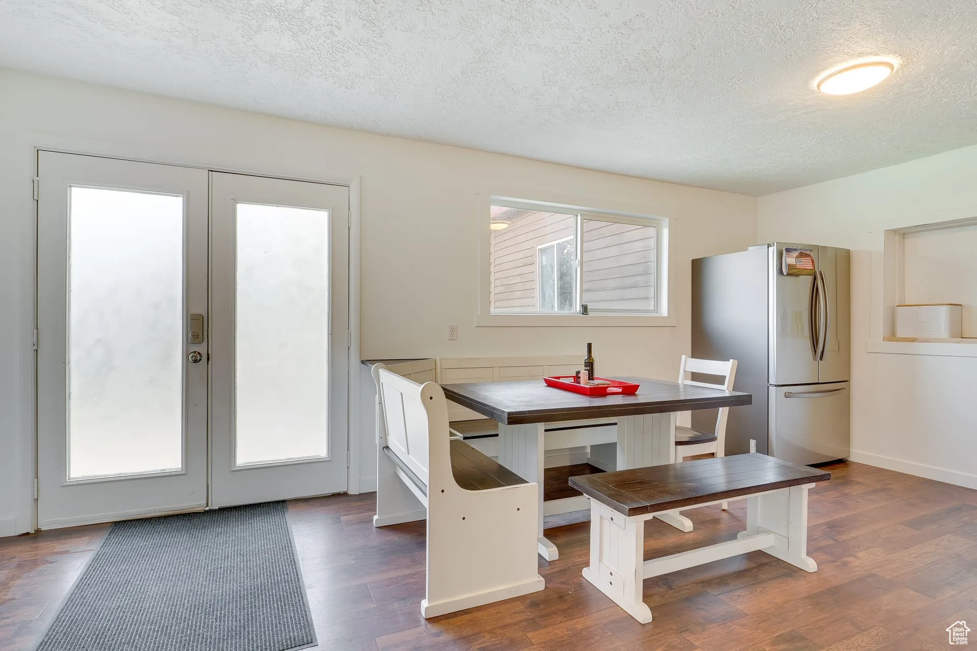 Dining area featuring a textured ceiling, french doors, and dark wood-style flooring