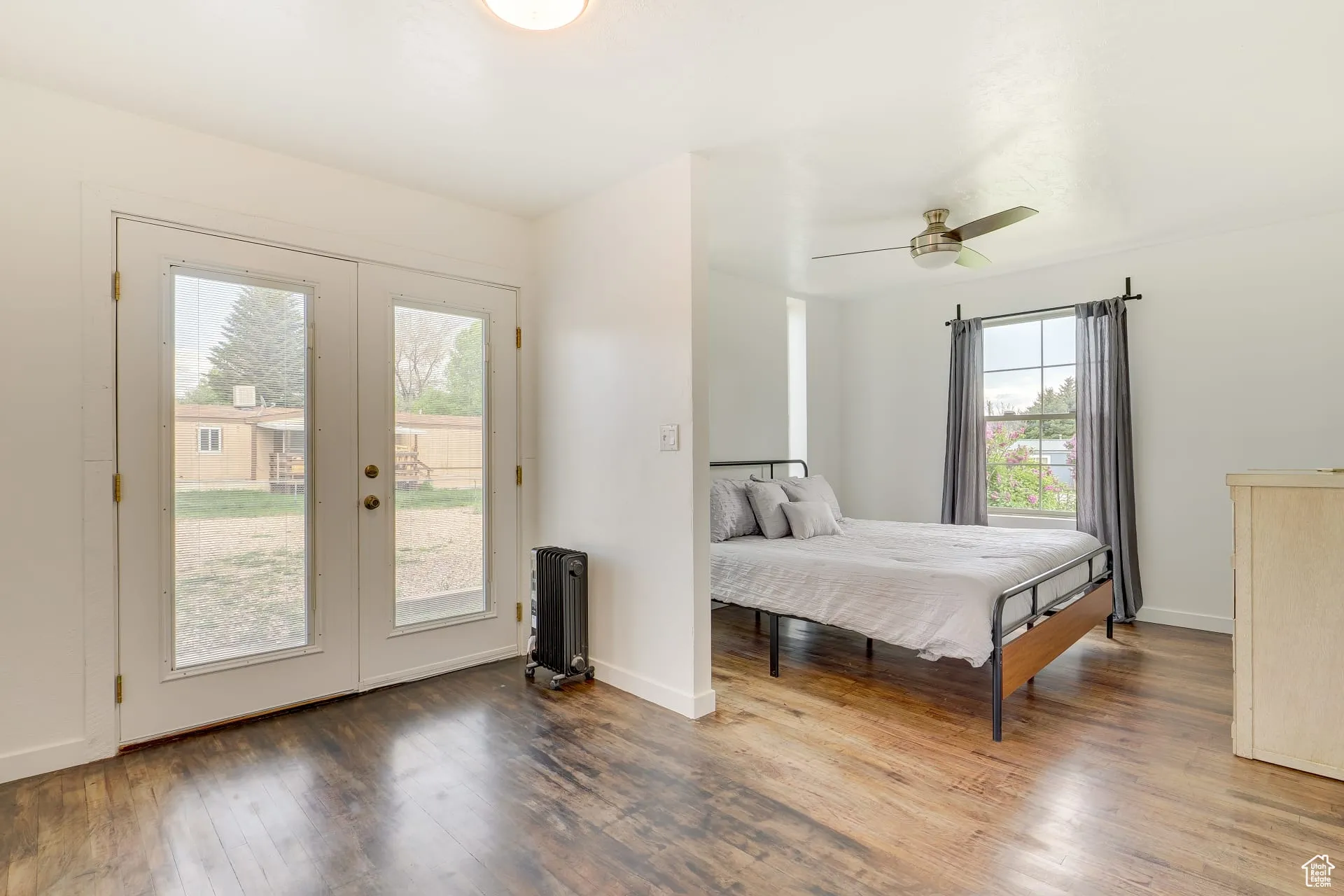 Bedroom with wood finished floors, access to outside, radiator heating unit, ceiling fan, and french doors