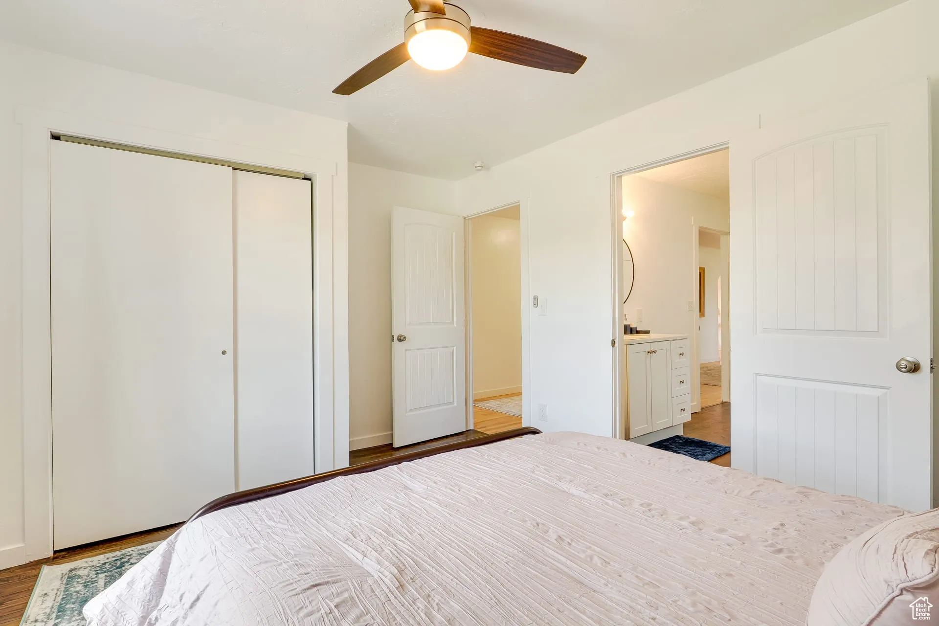 Bedroom featuring wood finished floors, ceiling fan, a closet, and ensuite bath