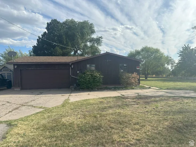 View of front of property featuring driveway, a front lawn, and a garage