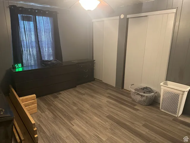 Bedroom with wood finished floors, two closets, and ceiling fan