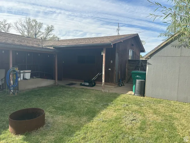 Back of property with a lawn and a shingled roof