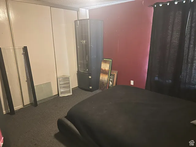 Bedroom featuring dark carpet and a textured ceiling