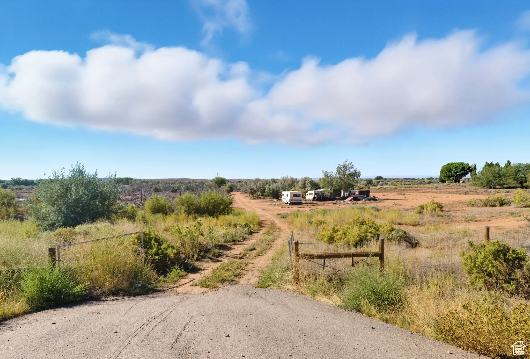 View of dirt / gravel driveway with a view of rural / pastoral area and a gated entry